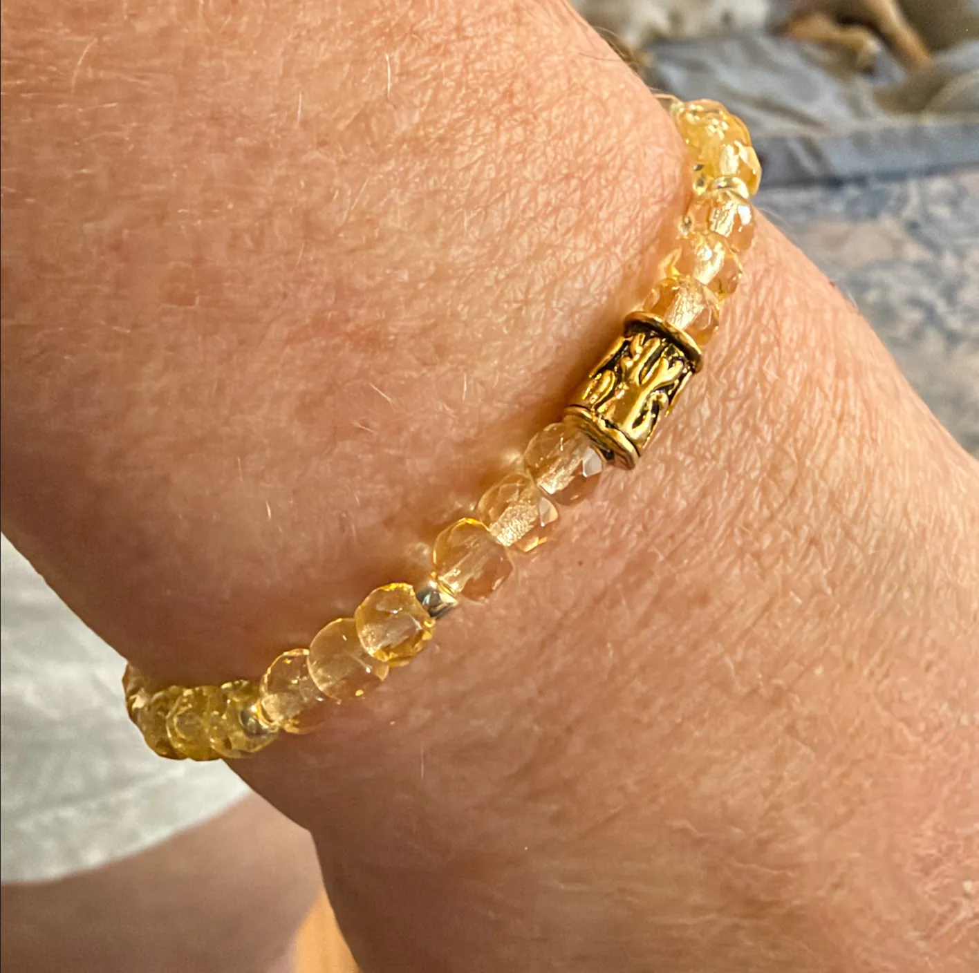 Citrine quartz beaded bracelet with brass decorative spacer bead, worn on wrist.