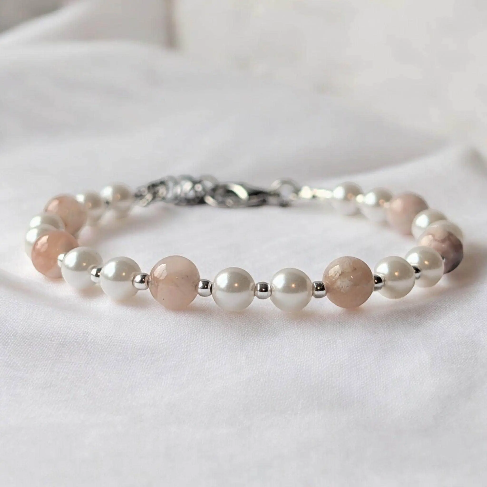Beaded bracelet with alternating rose quartz and white pearl beads separated by silver spacer beads, featuring a silver clasp.