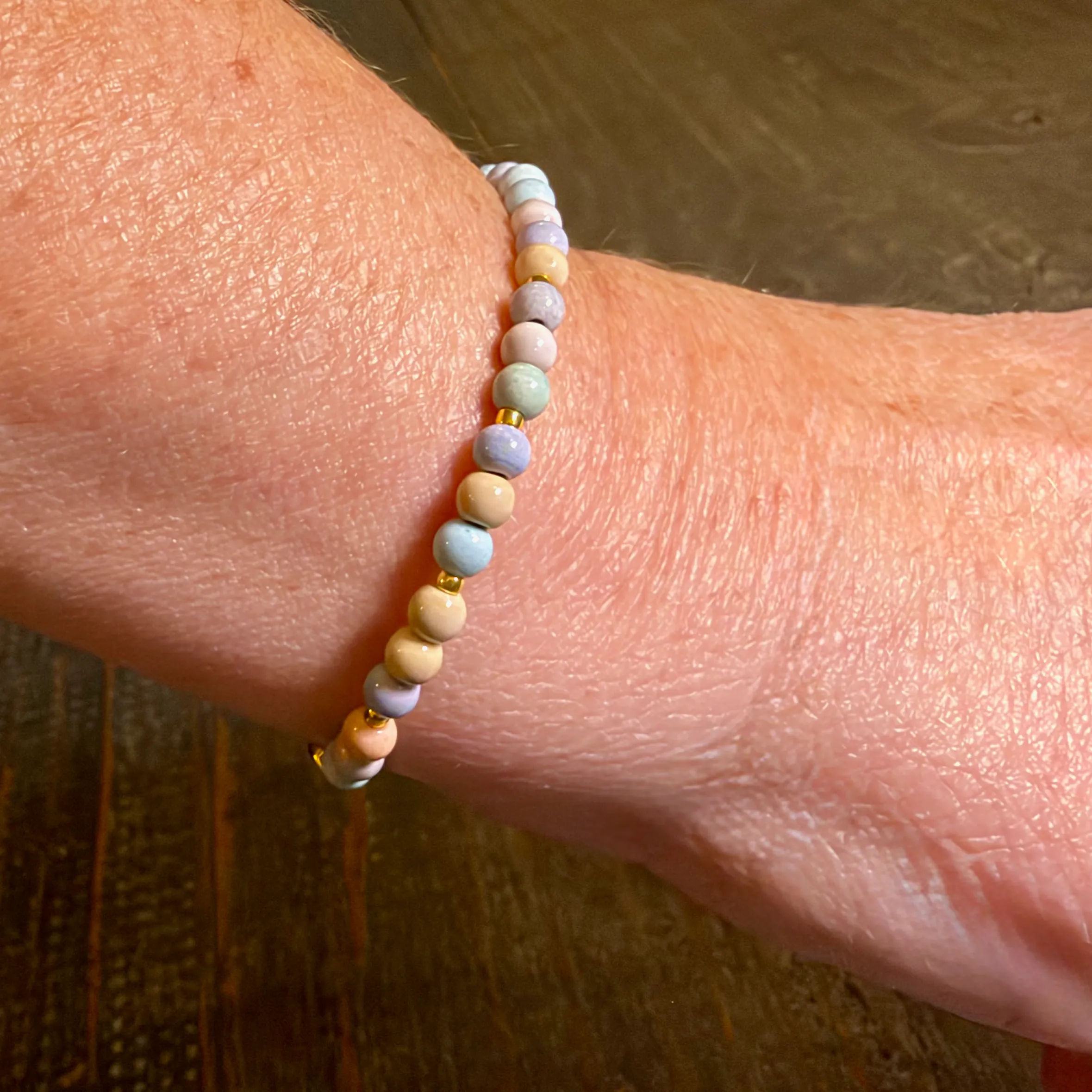 Beaded bracelet with pastel multicolored stones and gold spacer beads worn on a wrist.