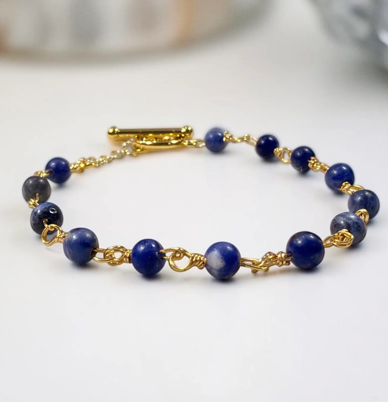 Gold-plated bracelet with deep blue lapis lazuli beads and decorative wire-wrapped spacers.
