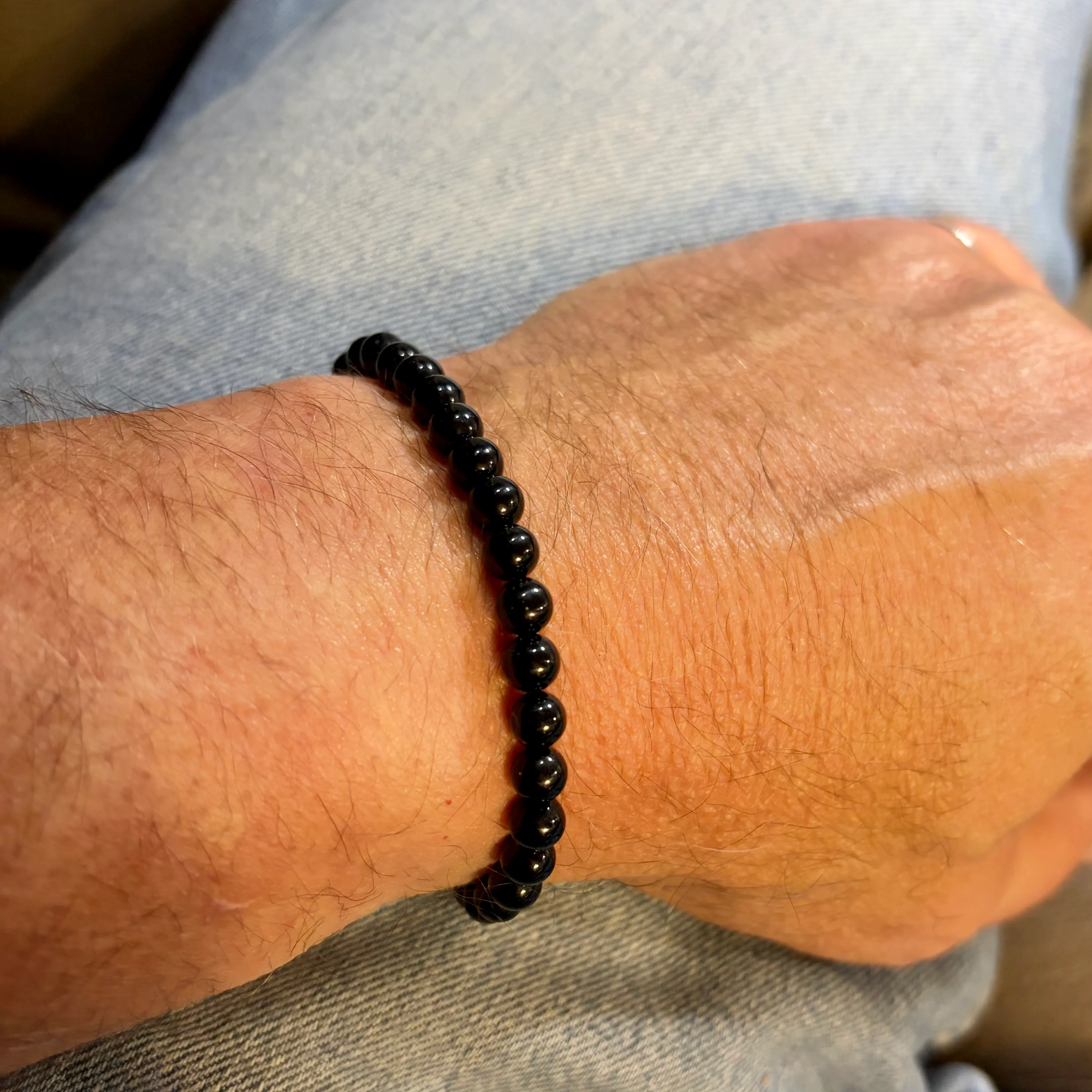 Black beaded bracelet worn on a man's wrist.