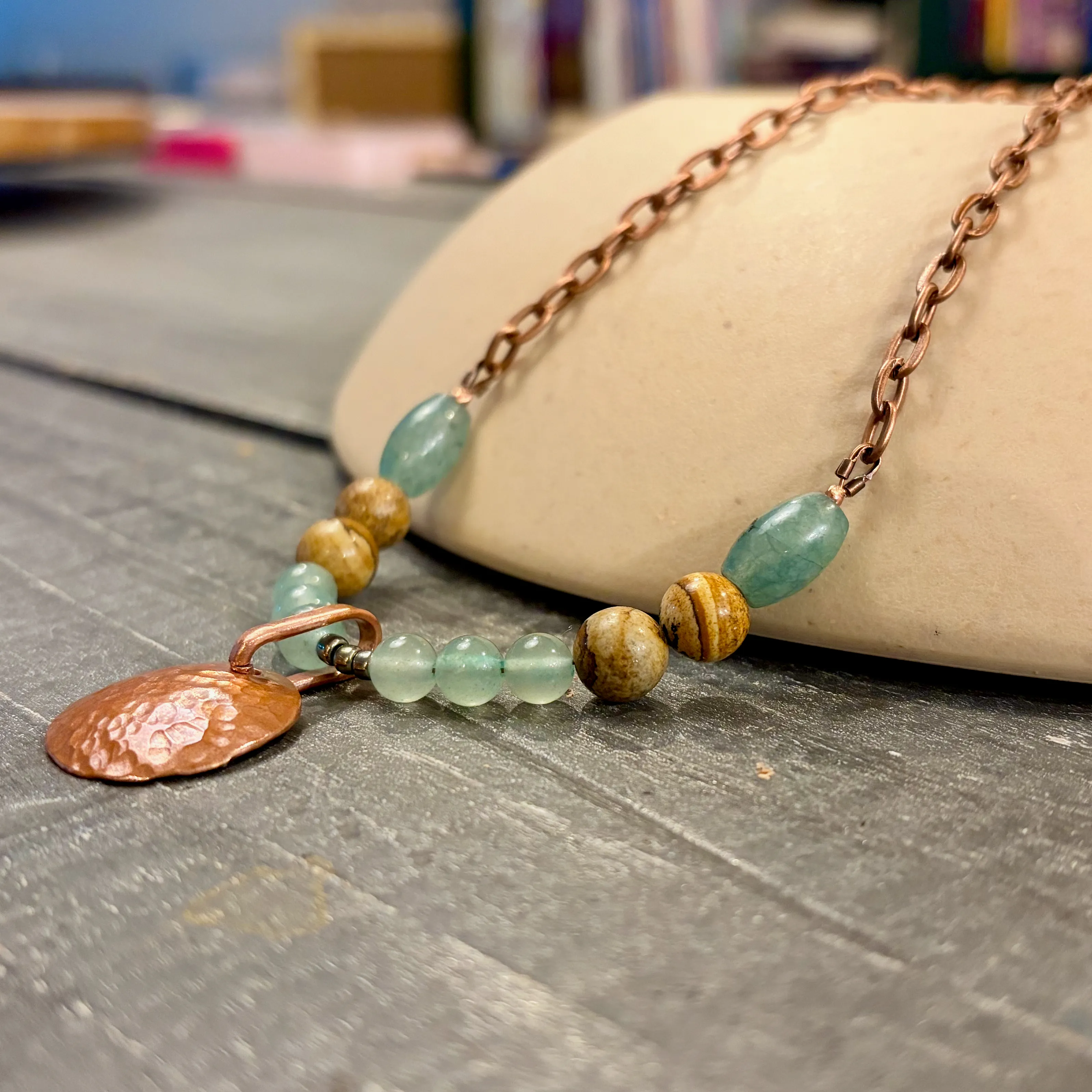 Handmade copper necklace with green aventurine and wooden beads featuring a textured copper leaf pendant.