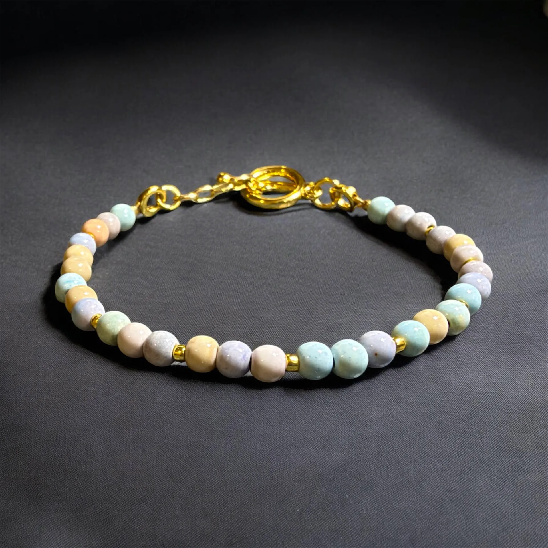 Beaded bracelet with pastel-colored gemstone beads and gold-tone metal spacers and clasp.