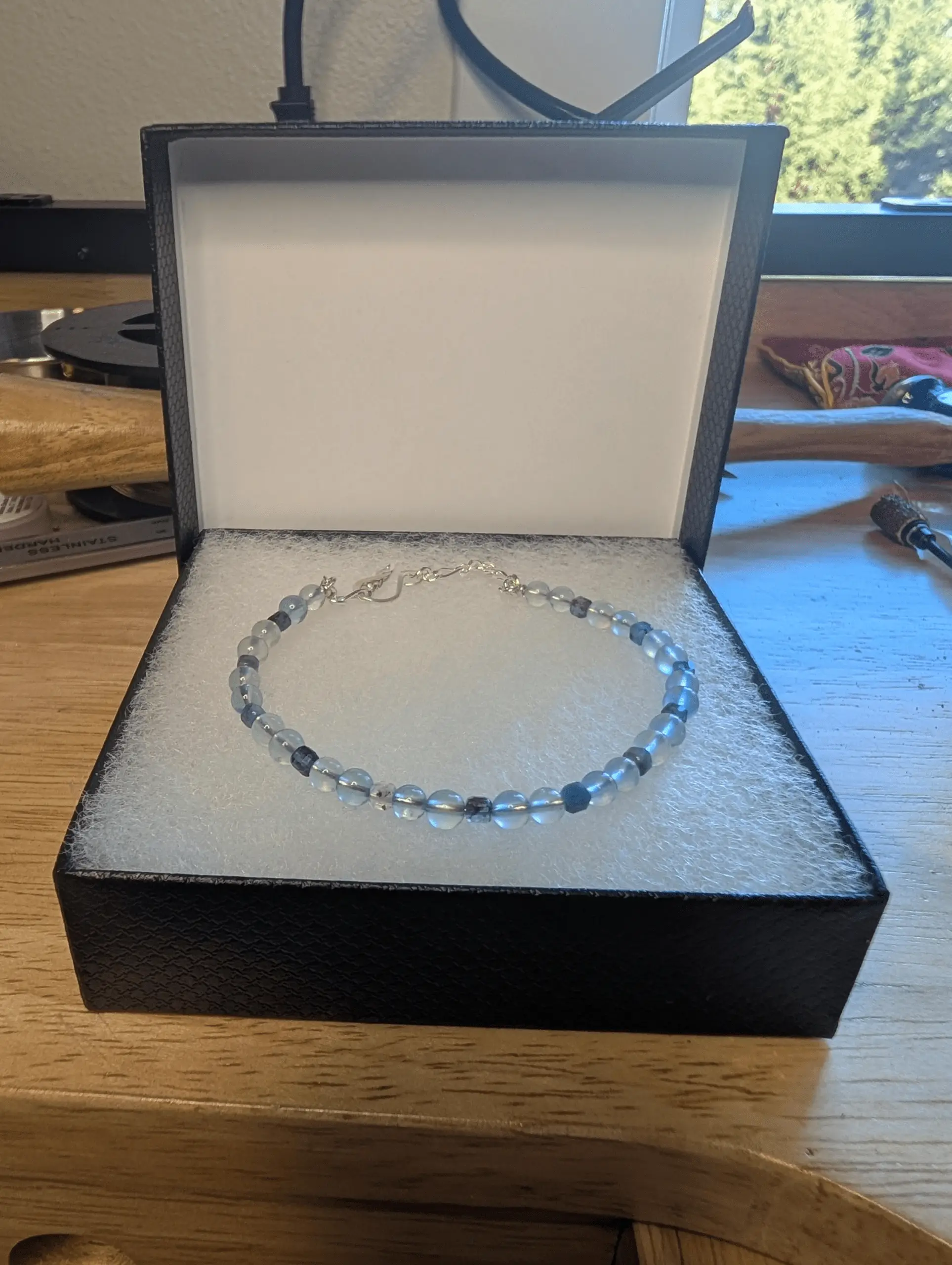 Beaded bracelet with clear and black stones on silver clasp displayed in open black jewelry box.