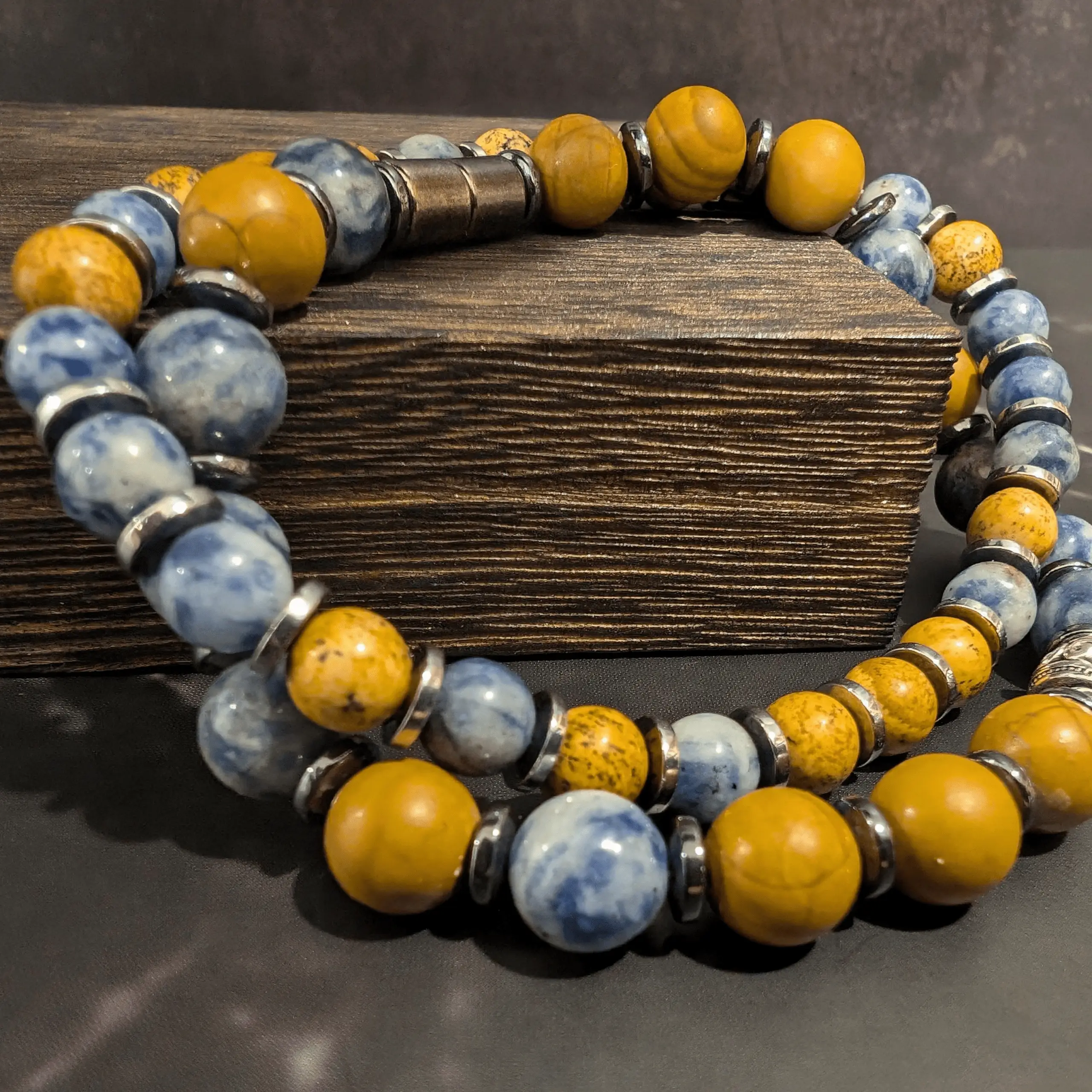 Beaded bracelet with alternating yellow and blue stone beads separated by silver metal spacers on a wooden surface.